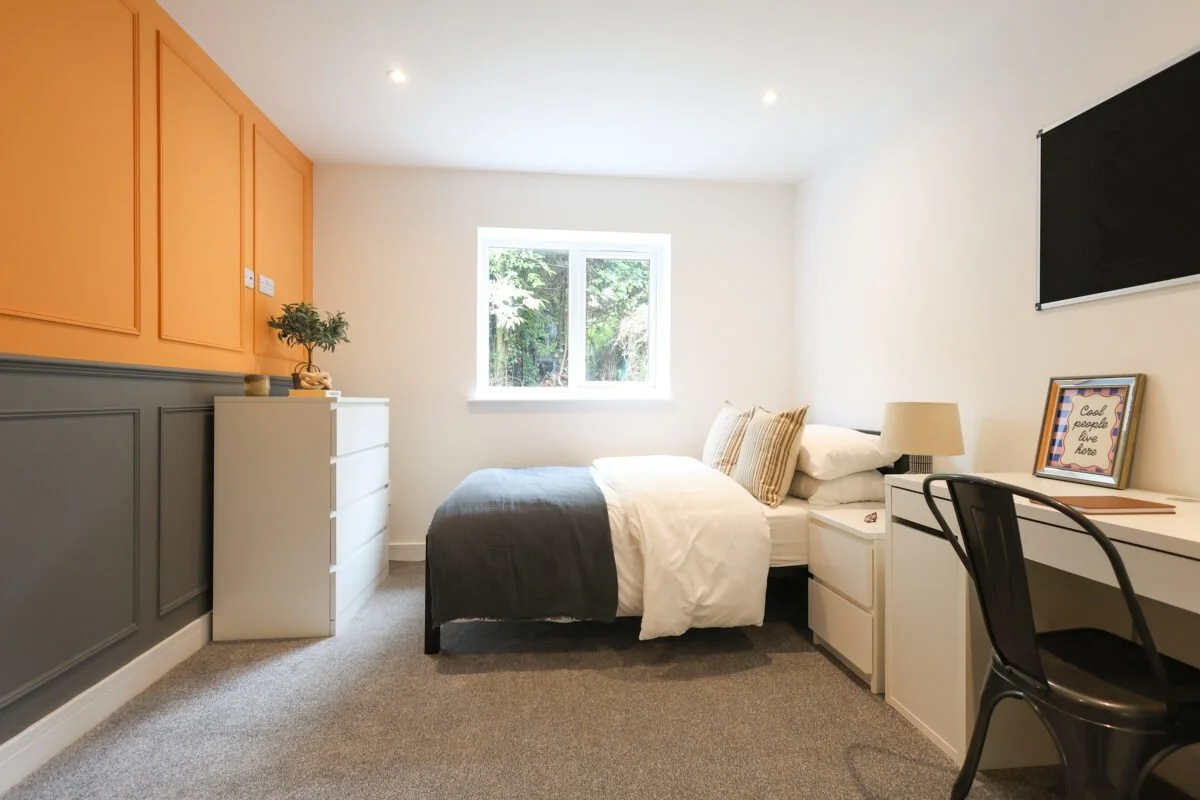 A bedroom with a bed, window, white and gray furniture, and decorative items.
