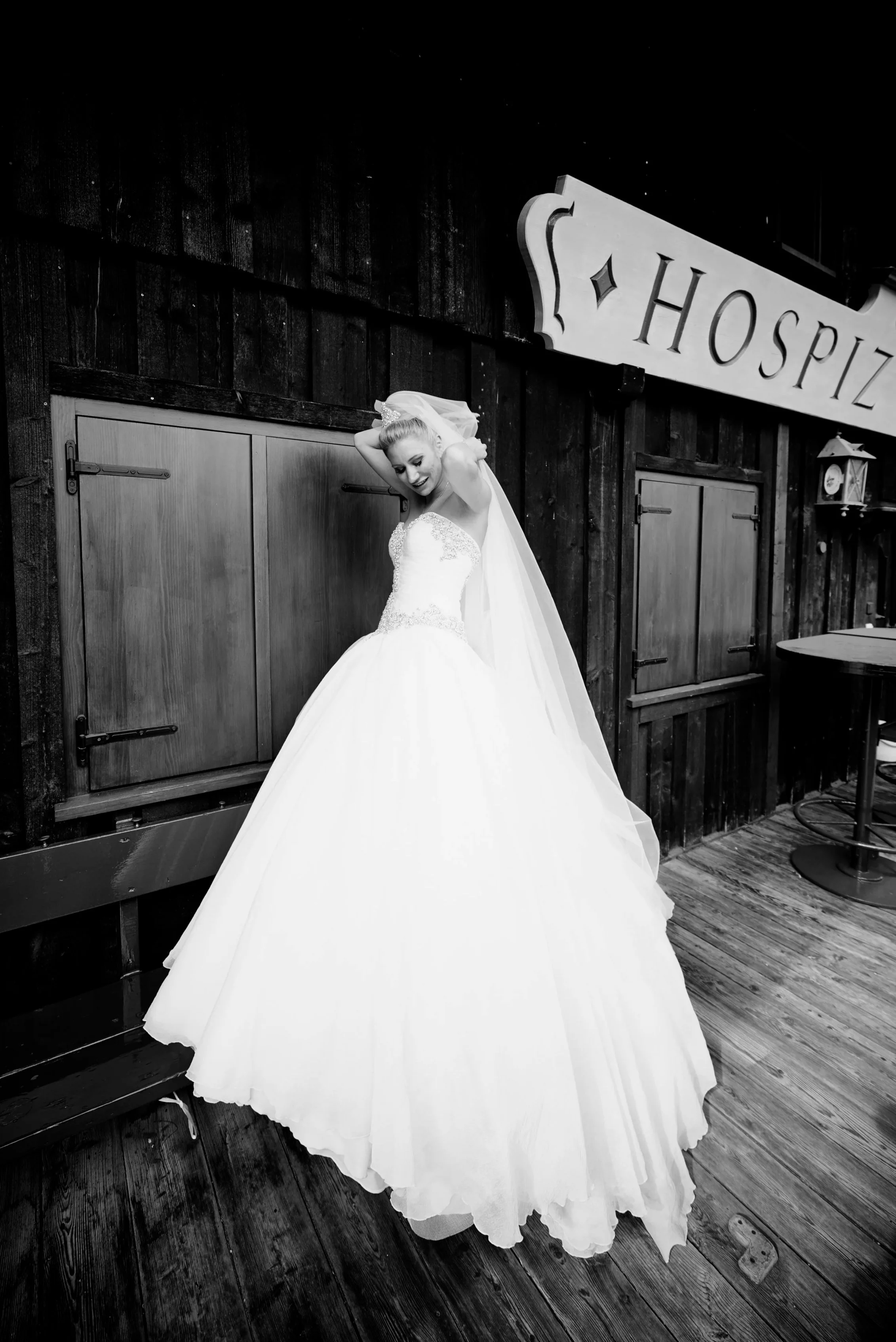 Schwarz-Weiß-Porträt einer Braut, die auf dem Balkon eines stilvollen Berghotels in Österreich steht