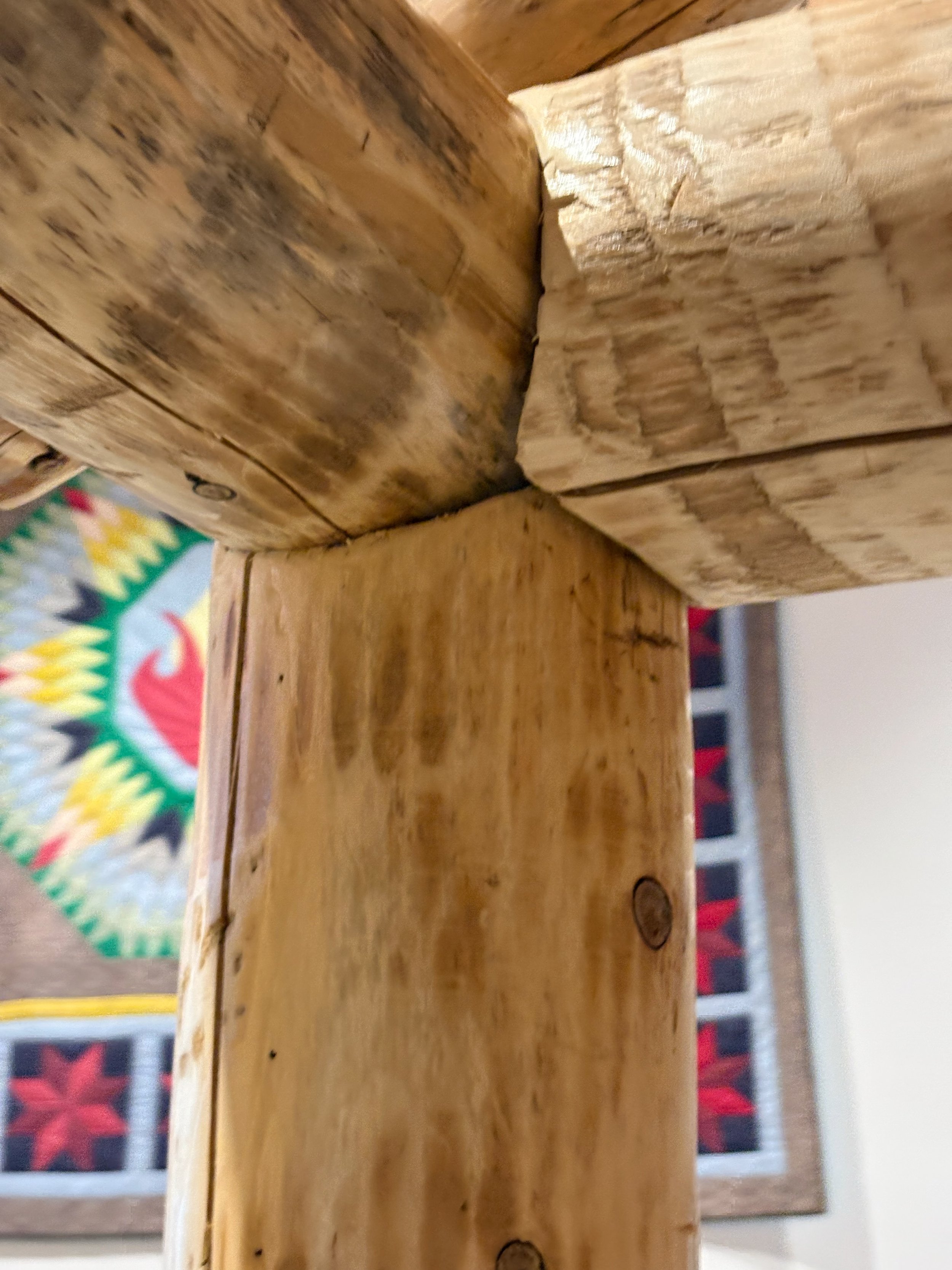 Close-up of the corner joint of vertical and horizontal wooden beams with visible wood grain and knots.