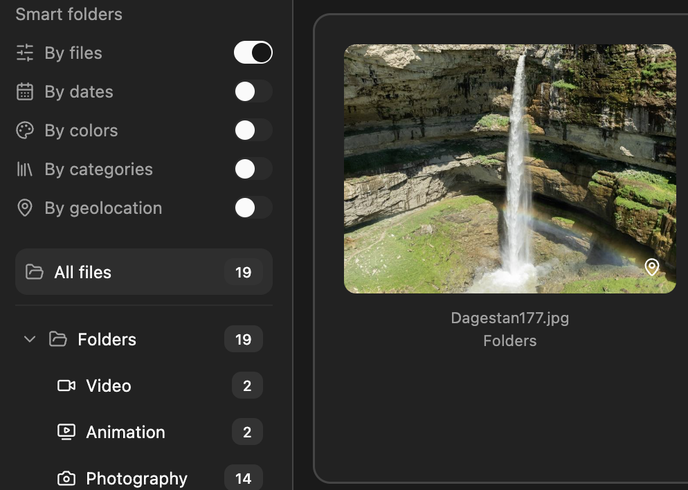 A tall waterfall cascading down from layered rock formations into a green, misty pool below, with small rainbow visible near the bottom of the waterfall.