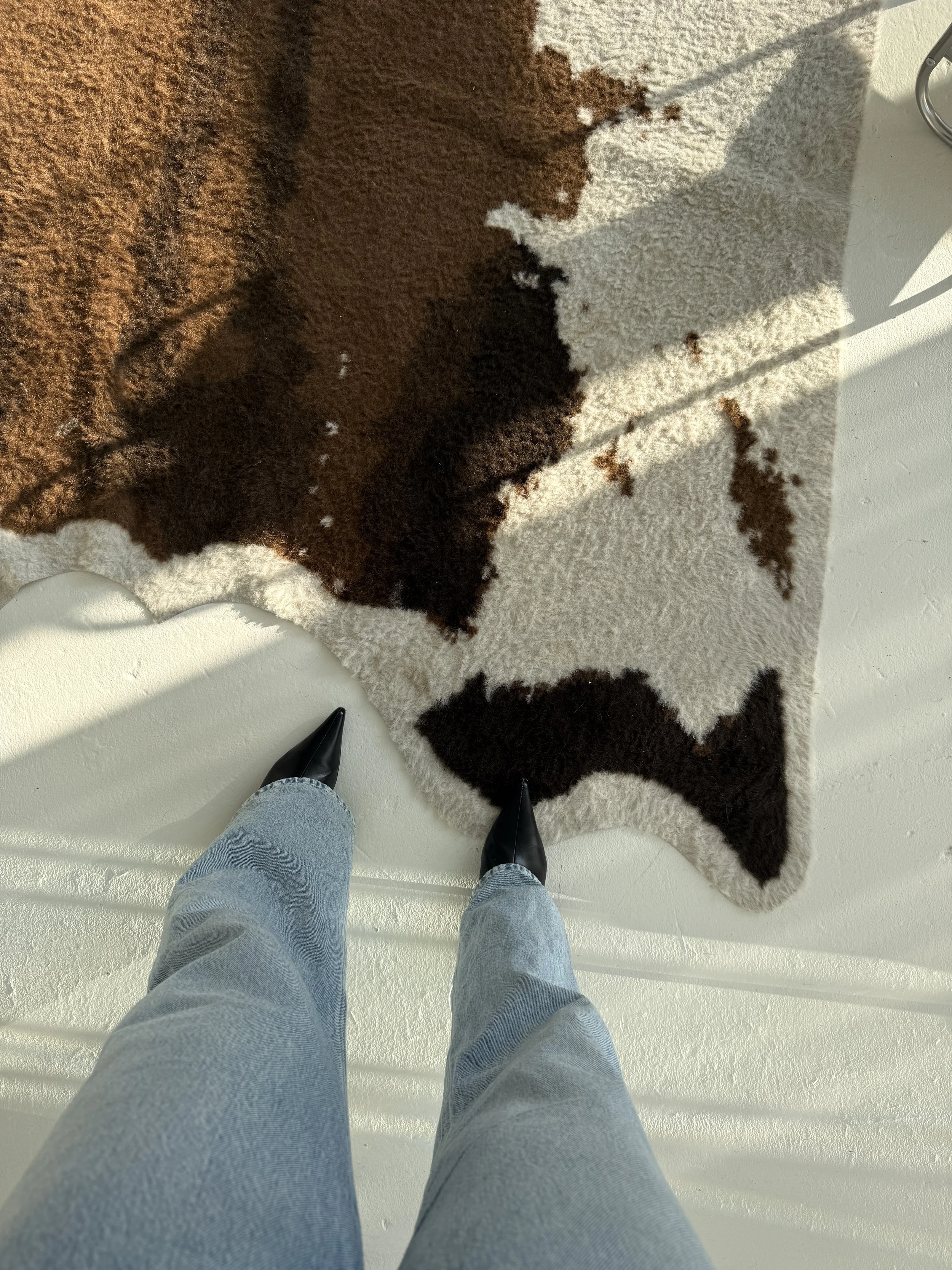 Birds eye view of boots on a cow print rug.