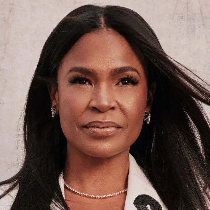 A portrait of a woman with long black hair, wearing earrings and a pearl necklace, against a neutral background.