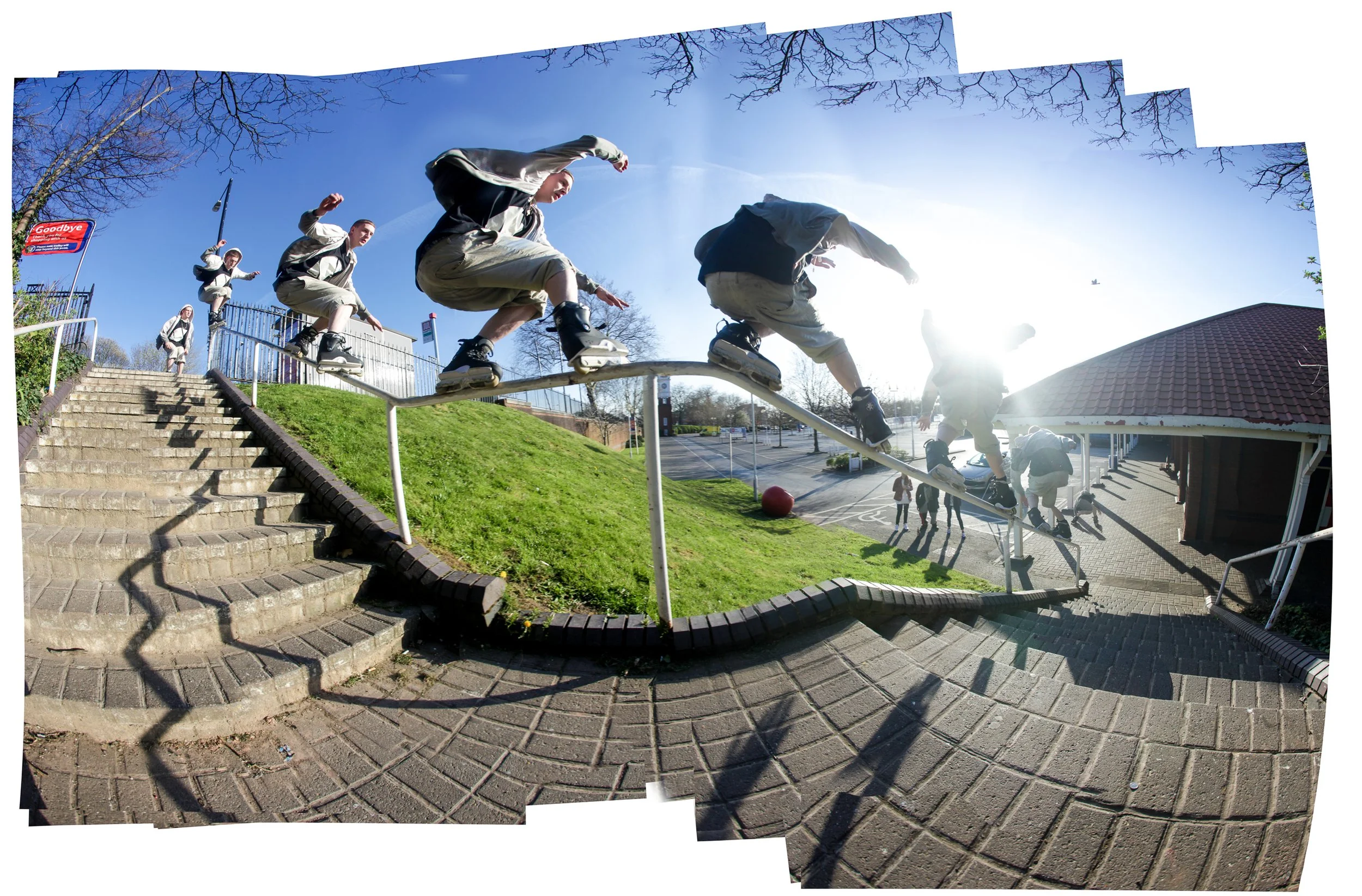 Sequence of skaters performing a skateboarding trick on a handrail outdoors on a sunny day, with stairs and a building in the background.