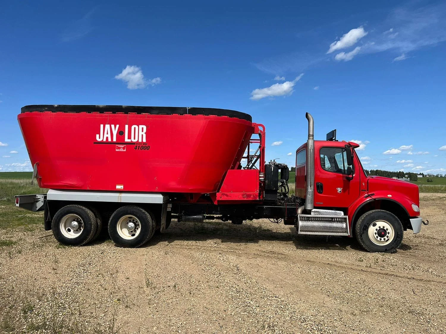 Full right side profile view of a red used Jaylor TM41000 truck-mounted vertical mixer on a tandem-axle Freightliner chassis.