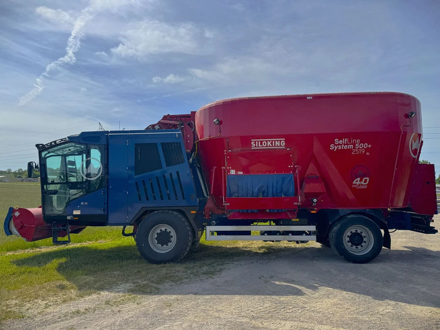 Left side profile view of a red and blue 2023 Siloking SelfLine 4.0 System 500+ 2519-27 self-propelled vertical TMR mixer wagon for sale at Siloking Canada.