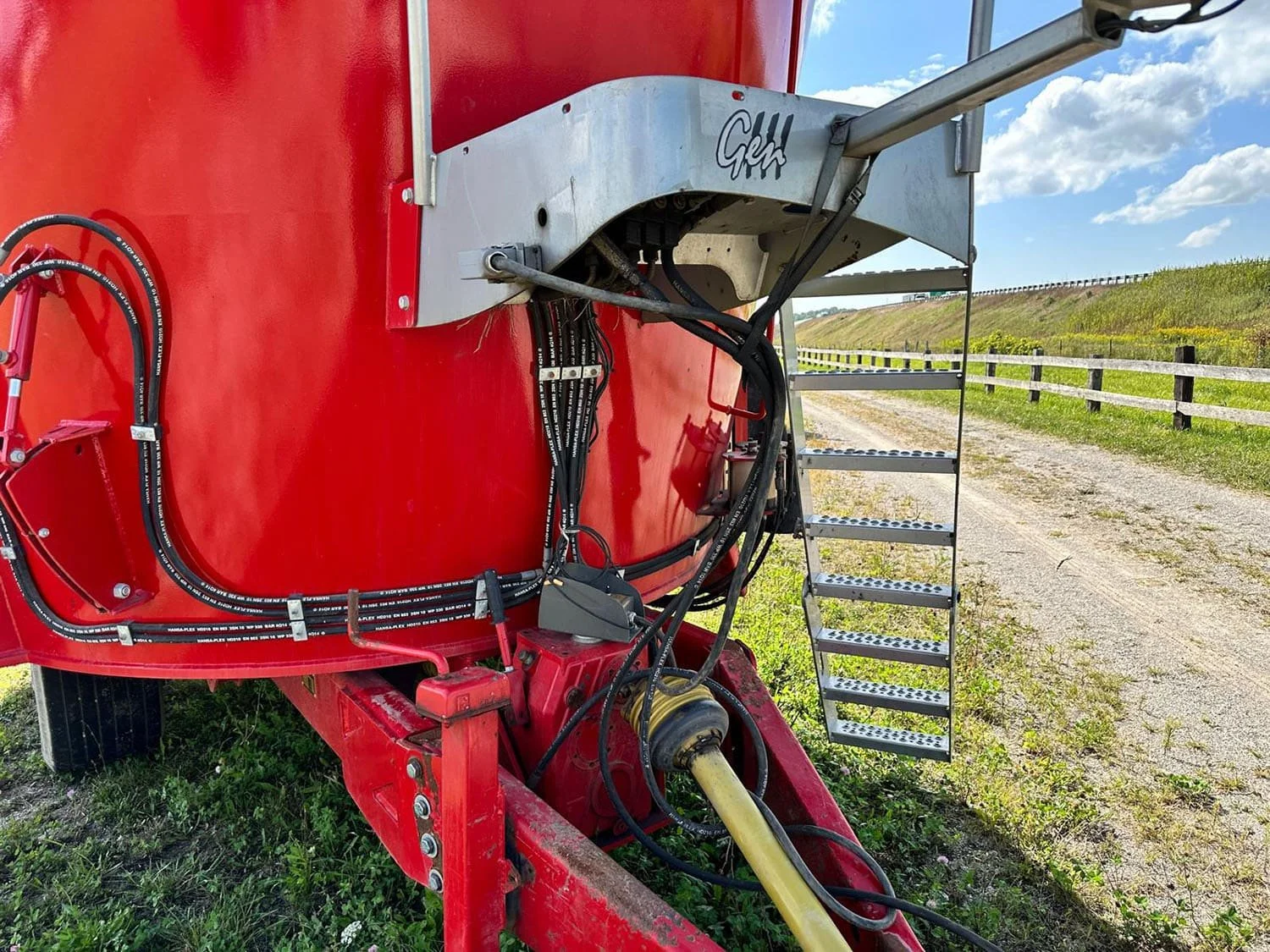 Detailed close-up view of the front drawbar hitch tongue, PTO drive shaft, and hydraulic line routing on a Peecon trailed mixer.