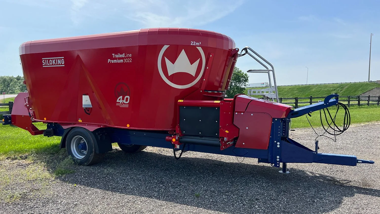 A parked 22 cubic meter Siloking TrailedLine Premium 3022 twin-auger pull-type vertical feed mixer wagon on a gravel shoulder during summer.