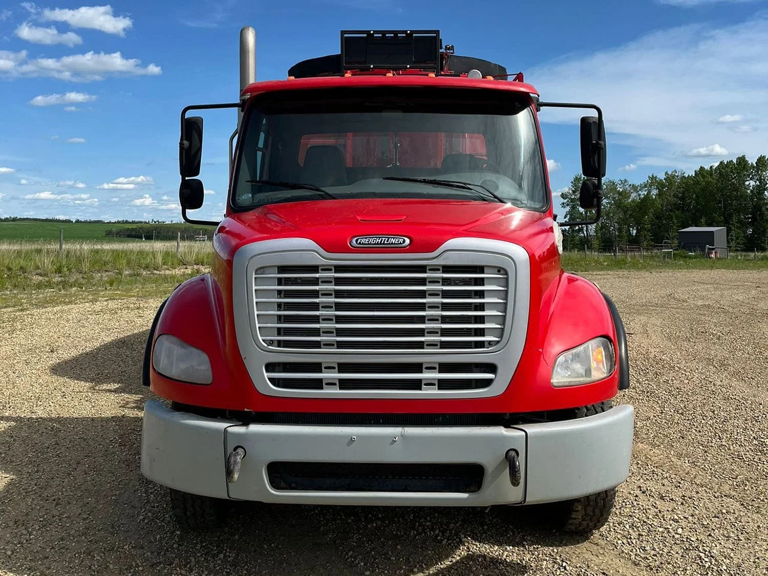 Straight-on front view of the red Freightliner chassis cab housing a Jaylor TM41000 truck-mounted vertical TMR feed mixer wagon.
