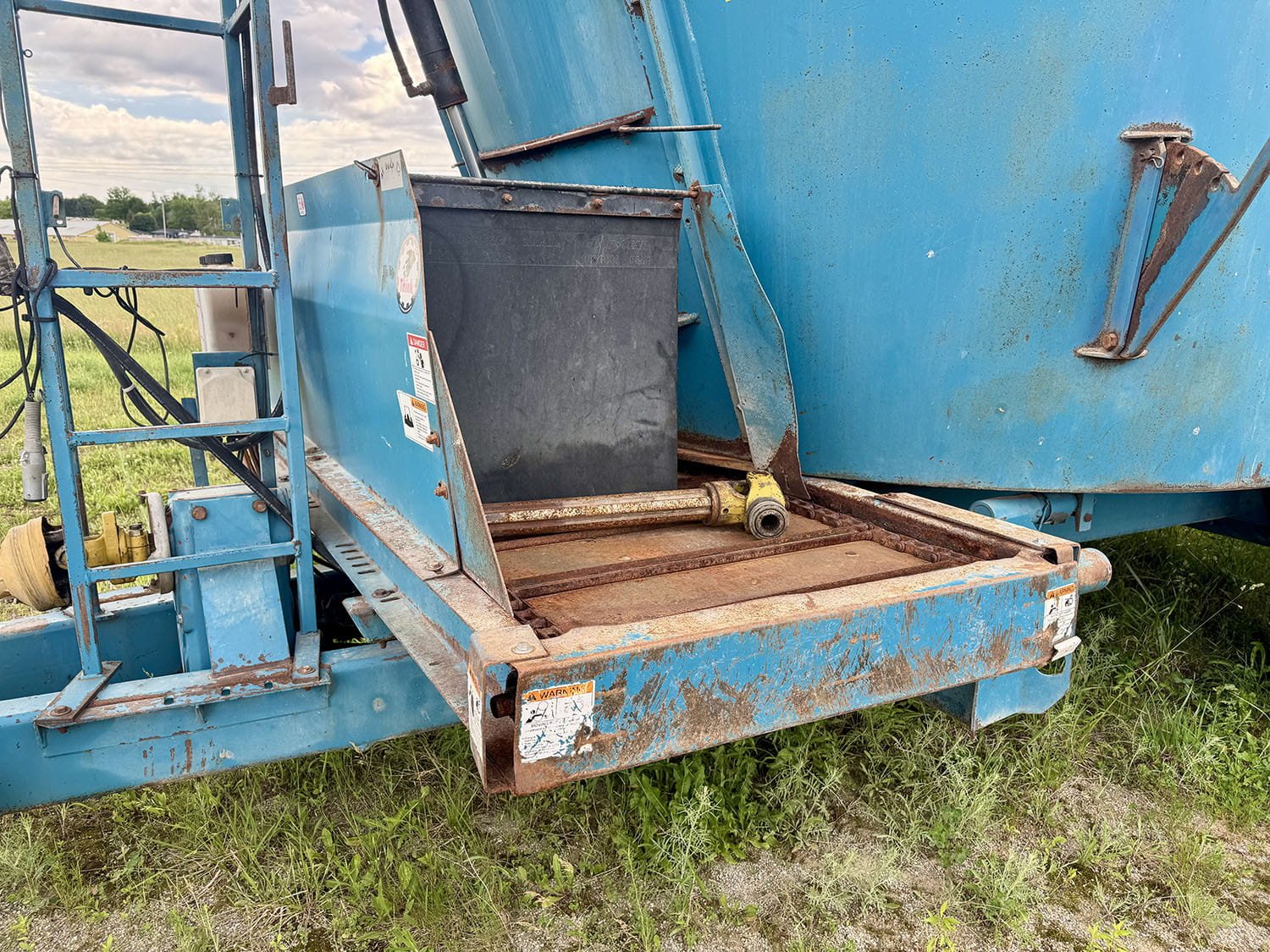 Close-up view of the left side flat cross conveyor chain and discharge door on a Lucknow 2290 vertical mixer.