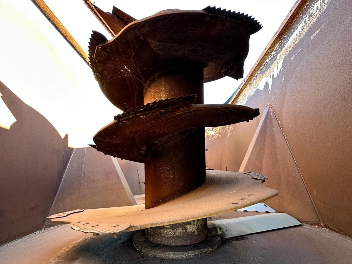 Interior view of the heavy-duty vertical mixing auger flighting and serrated knives inside a used 31 cubic meter Penta 1130HD feed mixer tub.