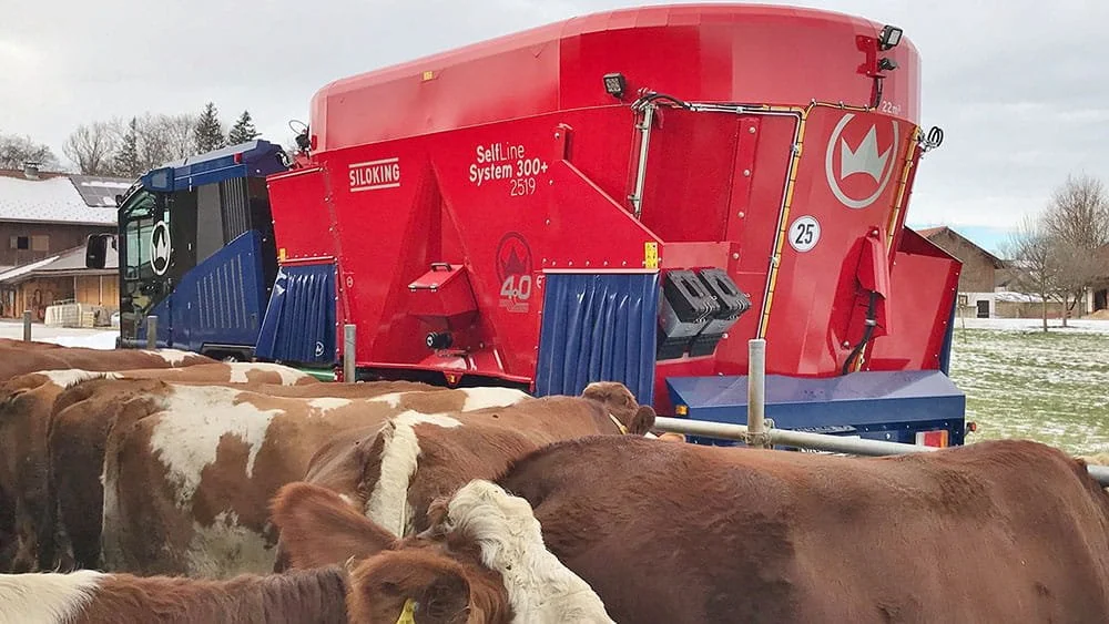 Rear perspective of a Siloking SelfLine System 300 plus 2519 self-propelled feed mixer driving along an outdoor bunk fence to feed beef cattle in winter.