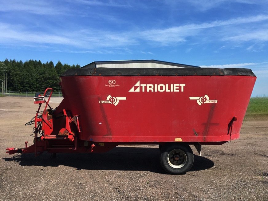 Full left side profile view of a red 2010 Trioliet Solomix 2 2000 pull-type feed mixer on a low-profile single-axle chassis.