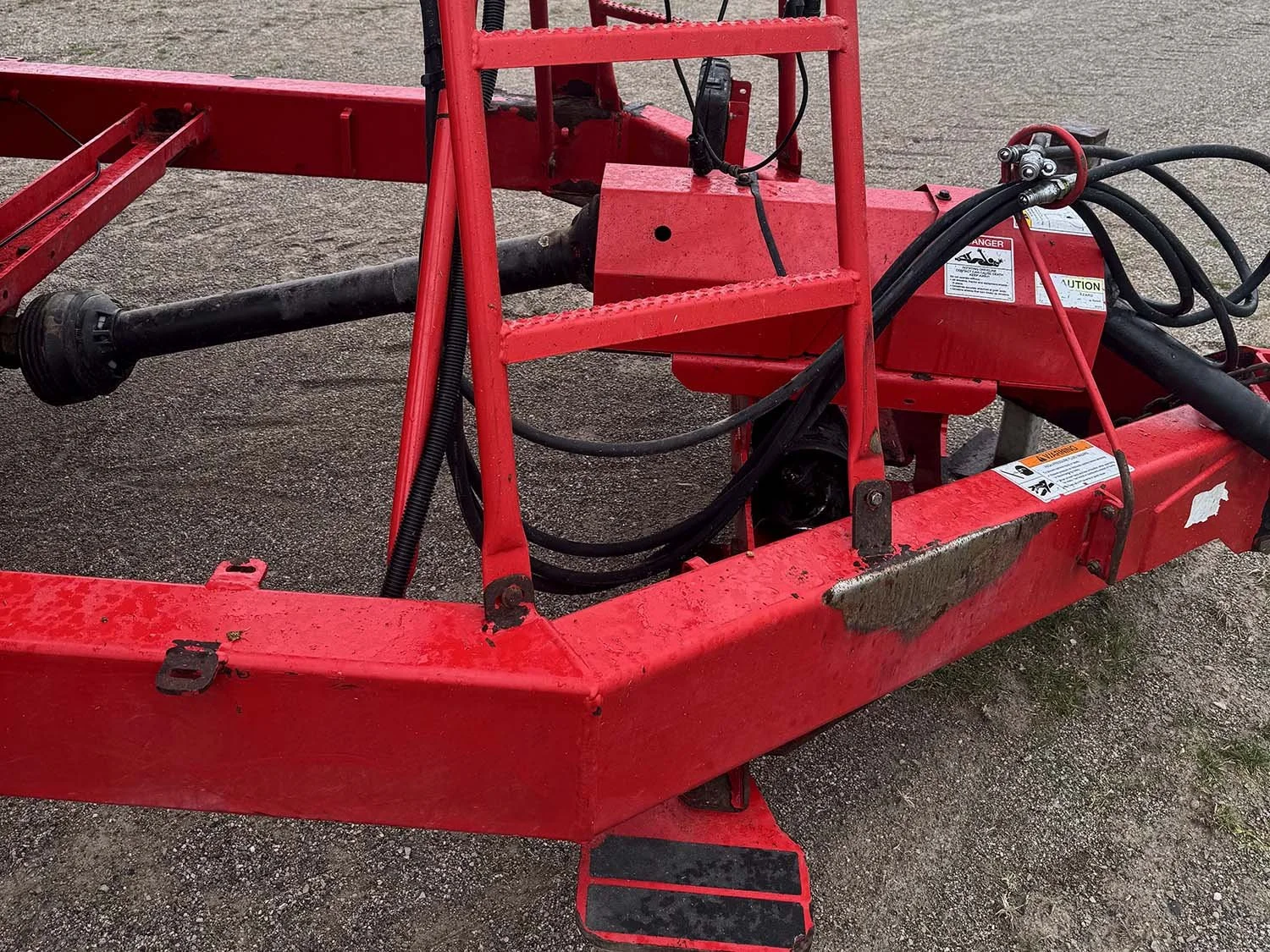 Detailed view of the front drawbar hitch tongue, PTO drive shaft connection, and operator platform ladder on a trailed NDE mixer wagon