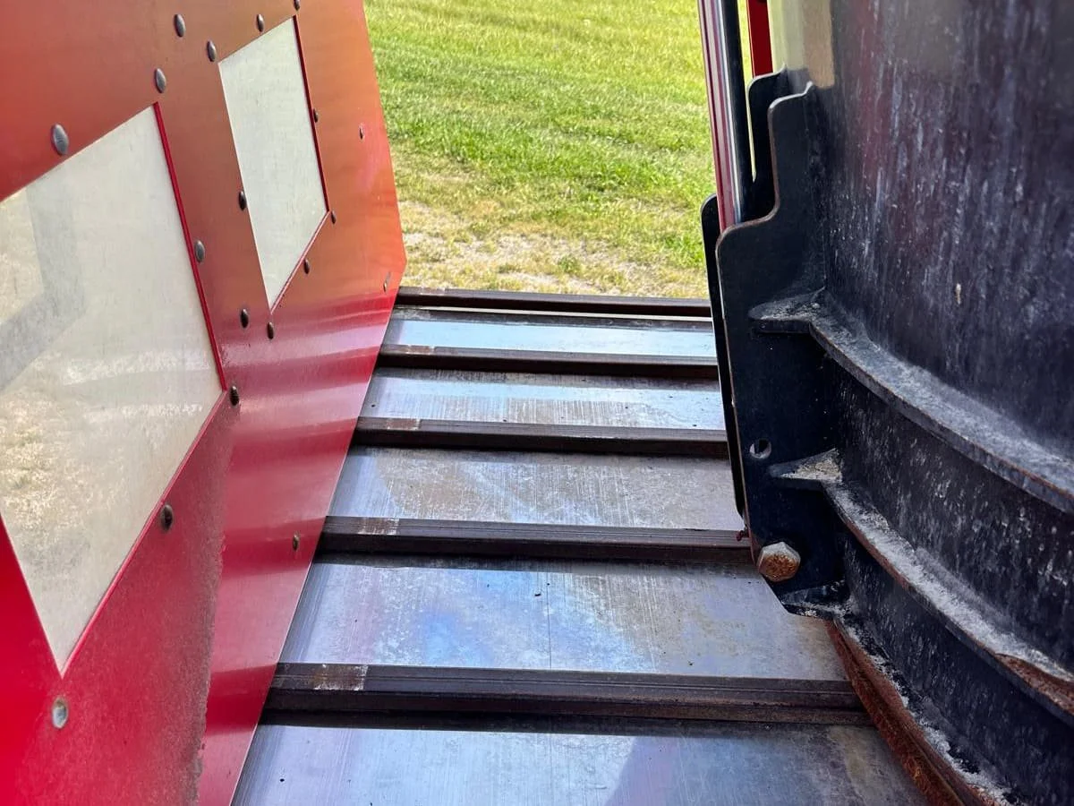 Close-up detailed view of the front cross conveyor discharge system featuring a premium stainless steel slider bed floor on a TMR mixer.