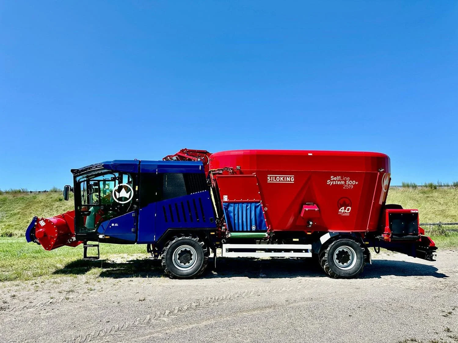 Left side profile view of a new red and blue Siloking SelfLine 4.0 System 500+ 2519-22 4x4 self-propelled vertical feed mixer showcasing the premium driver cab layout and left-hand discharge conveyor.