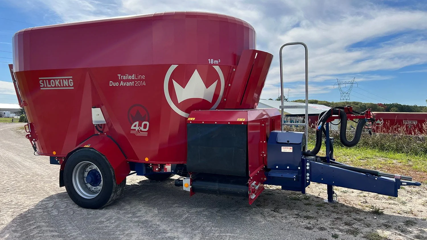 Three-quarter view of an 18m³ Siloking TrailedLine Duo Avant 2014 twin-auger feed wagon parked on a rural gravel lane under a cloudy summer sky.