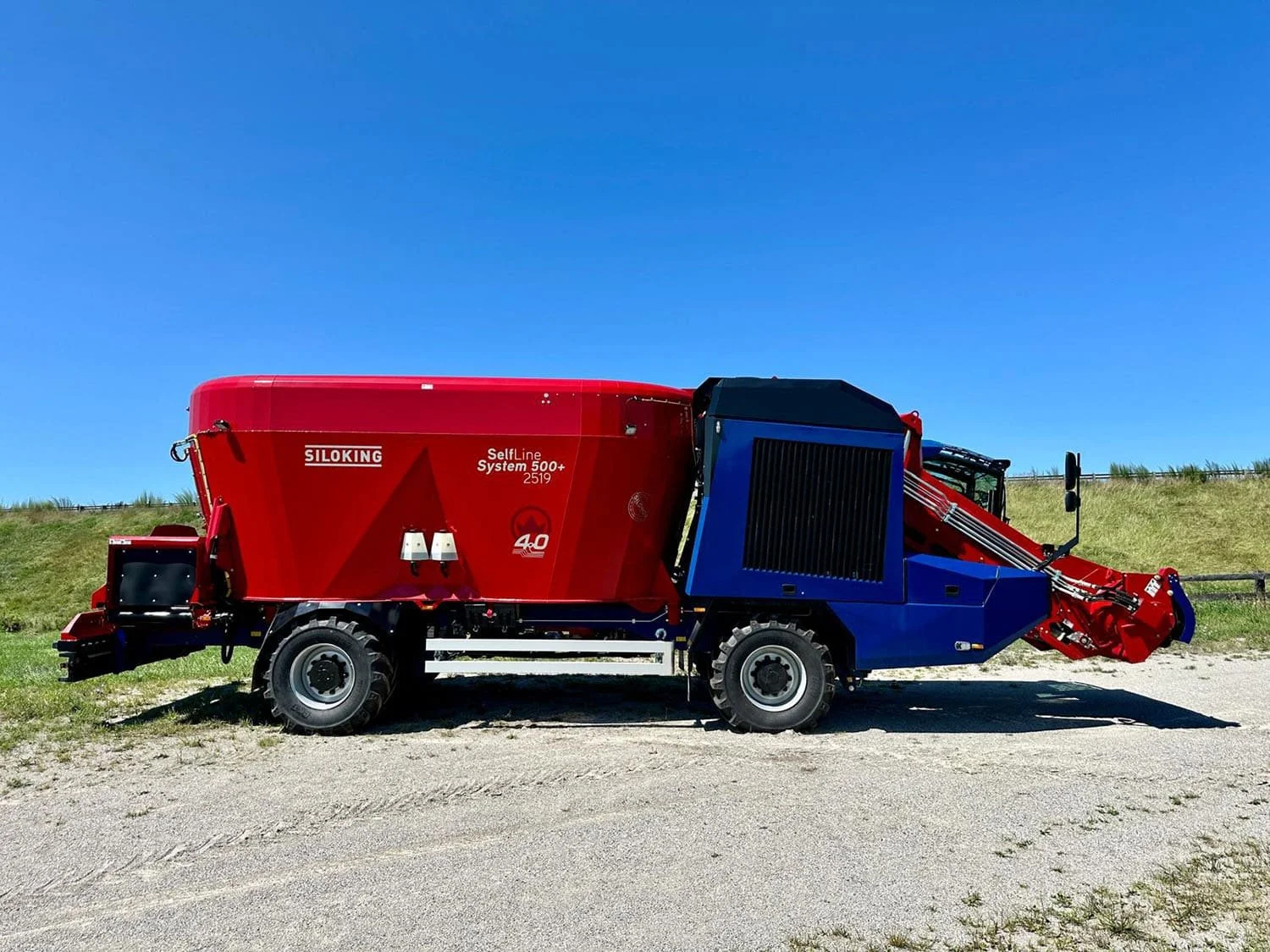 Right side profile view of a new red and blue Siloking SelfLine 4.0 System 500+ 2519-22 4x4 self-propelled TMR feed mixer showcasing the engine cooling package and silage milling arm.