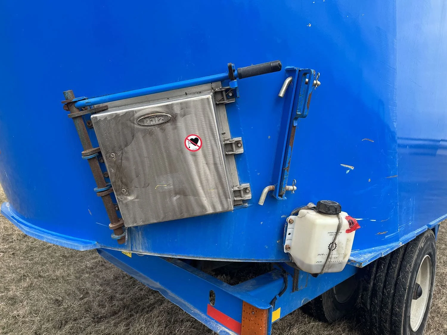 Close-up view of the stainless steel cleanout door and built-in rare earth tramp metal magnet assembly on a Patz vertical mixer tub.