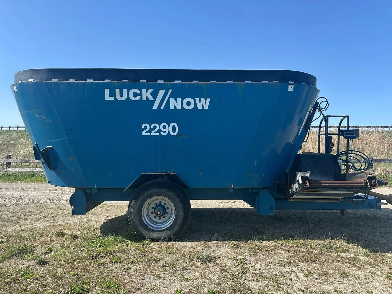 Right side profile view of a used blue Lucknow 2290 trailed twin-auger vertical TMR feed mixer wagon featuring a rubber tub extension and single axle for sale at Siloking Canada.