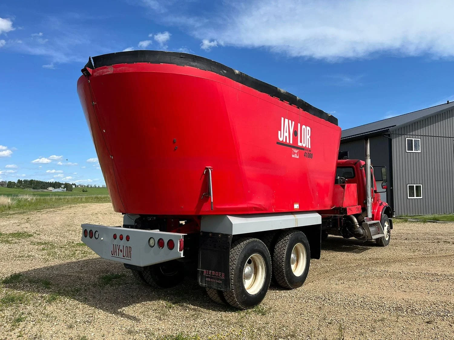 Rear right three-quarter perspective view of the red commercial mixing tub on a Jaylor TM41000 commercial truck mixer showing the custom bumper guard.