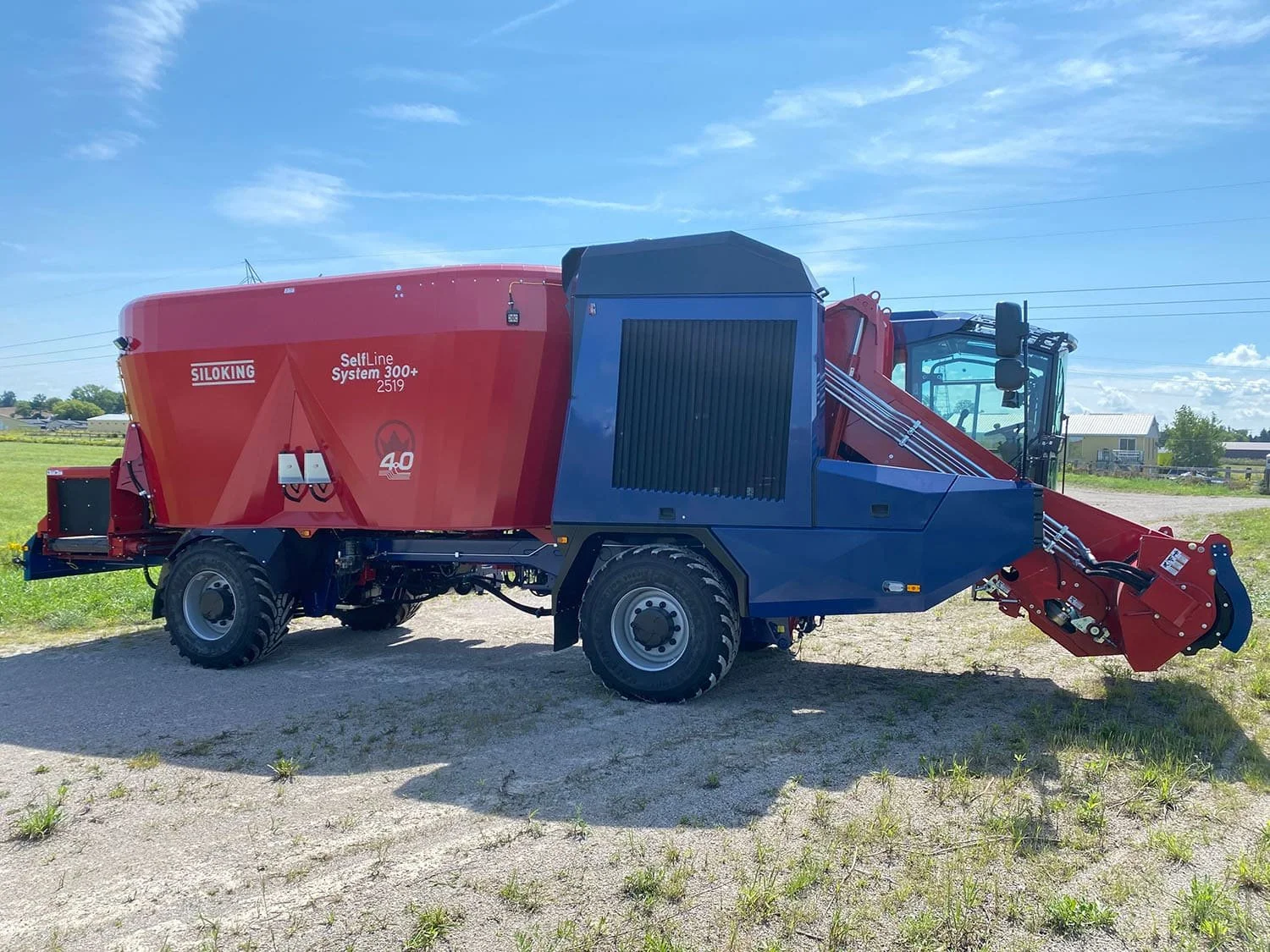 Right side profile view of a new red and blue Siloking SelfLine 4.0 System 300+ 2519-22 4x4 self-propelled mixer showing the engine cooling shroud and milling arm.