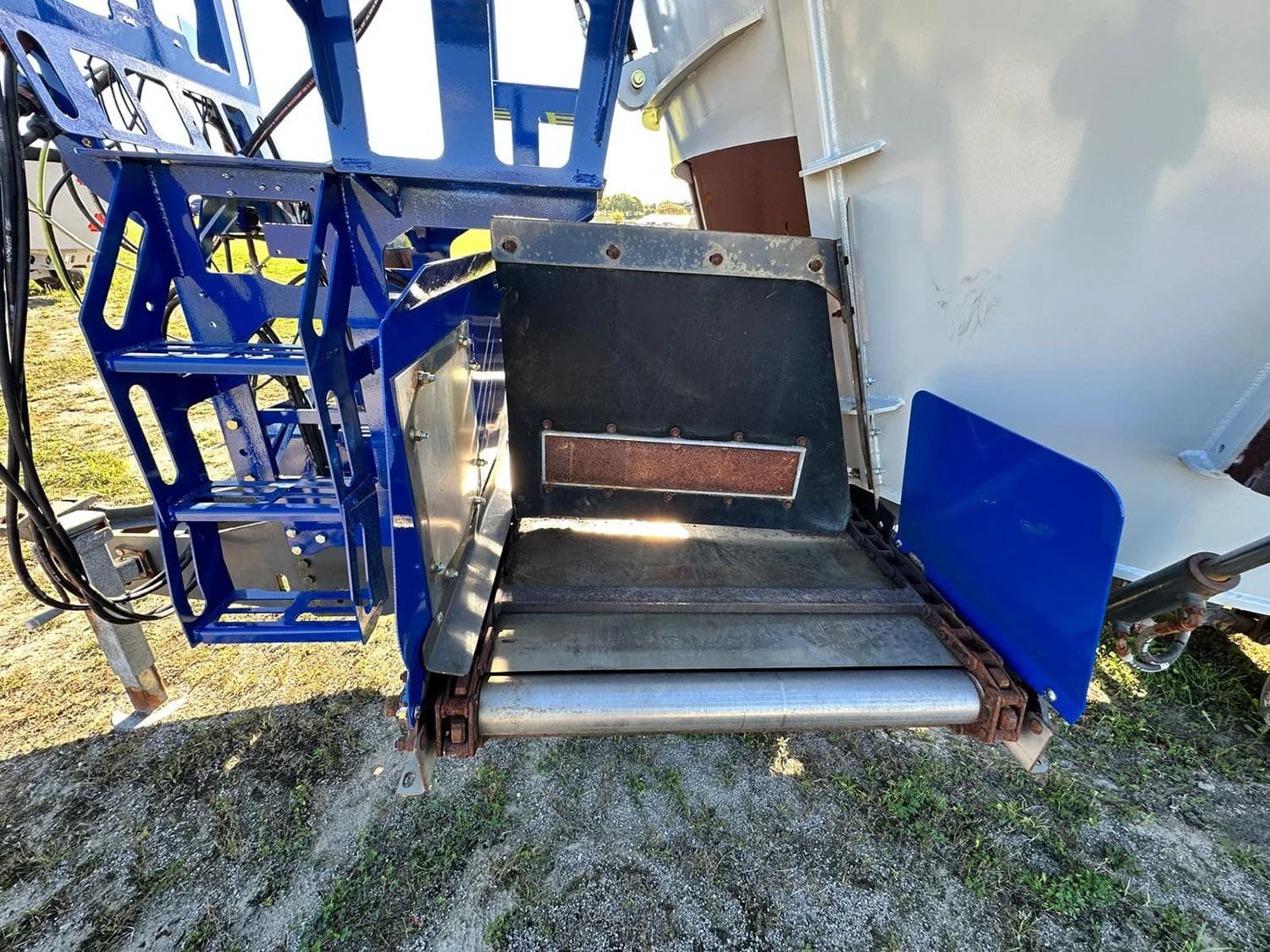 Detailed close-up view of the stainless steel front cross conveyor bed and right-hand discharge door on a Penta TMR mixer wagon.