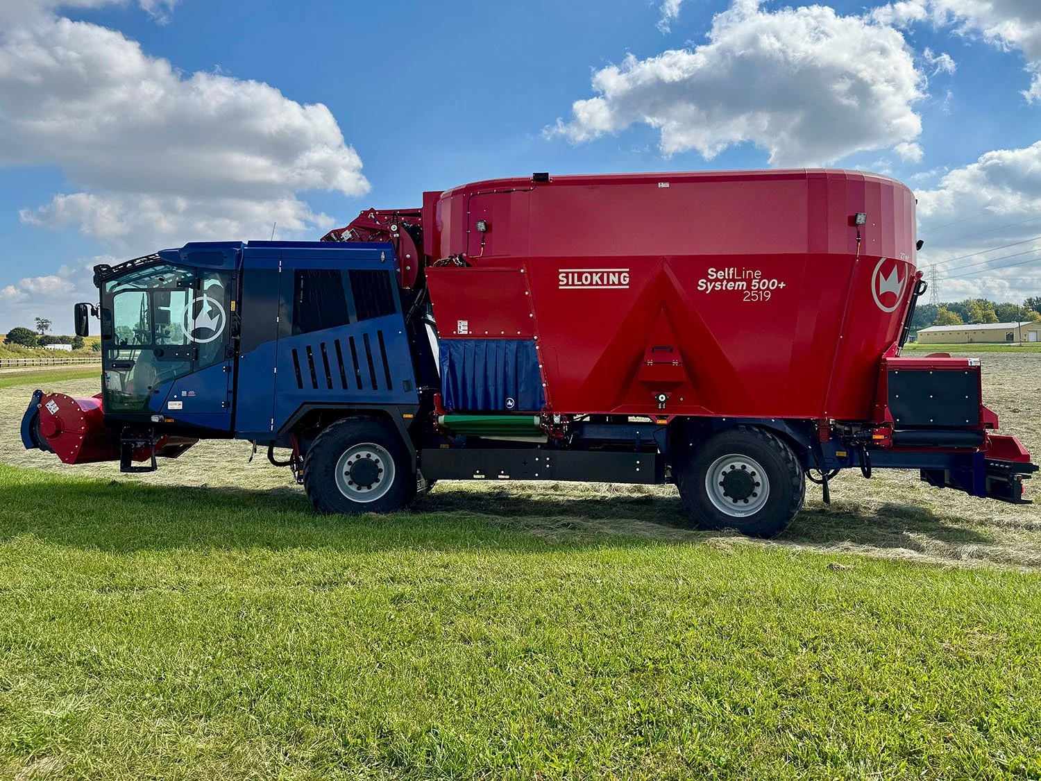 New red and blue SILOKING SelfLine 4.0 System 500+ 2519-27 4x4 self-propelled TMR mixer wagon with high-reach loading arm raised