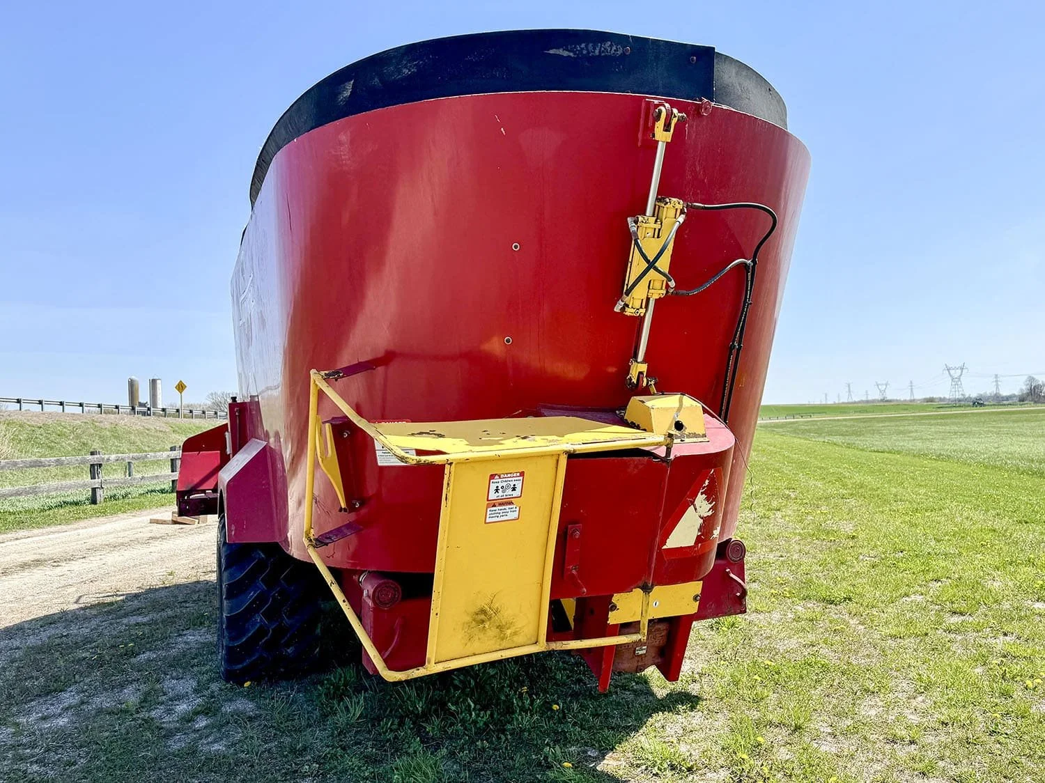 Rear view of a Supreme International 1000T vertical feed mixer wagon showing the integrated yellow rear chopper attachment and hydraulic cylinder.