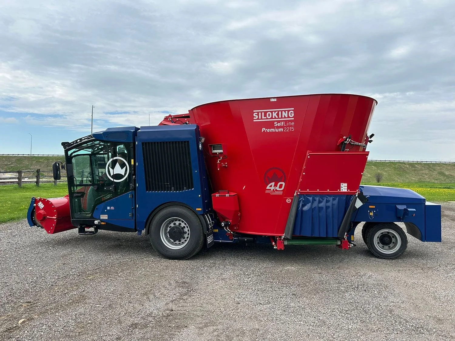 Left side profile view of a new red and blue Siloking SelfLine 4.0 Premium 2215-15 self-propelled TMR mixer showcasing the driver cab, hydraulic silage milling arm, and left-hand discharge conveyor.