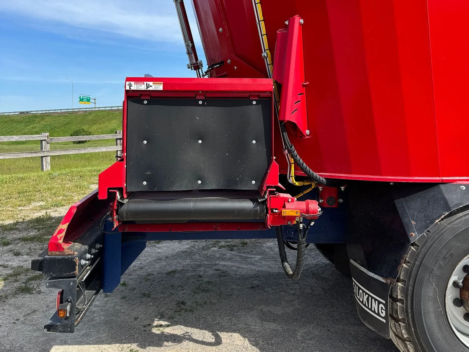 Detailed close-up rear view of the discharge cross conveyor assembly featuring hydraulic side shift on a Siloking self-propelled mixer.