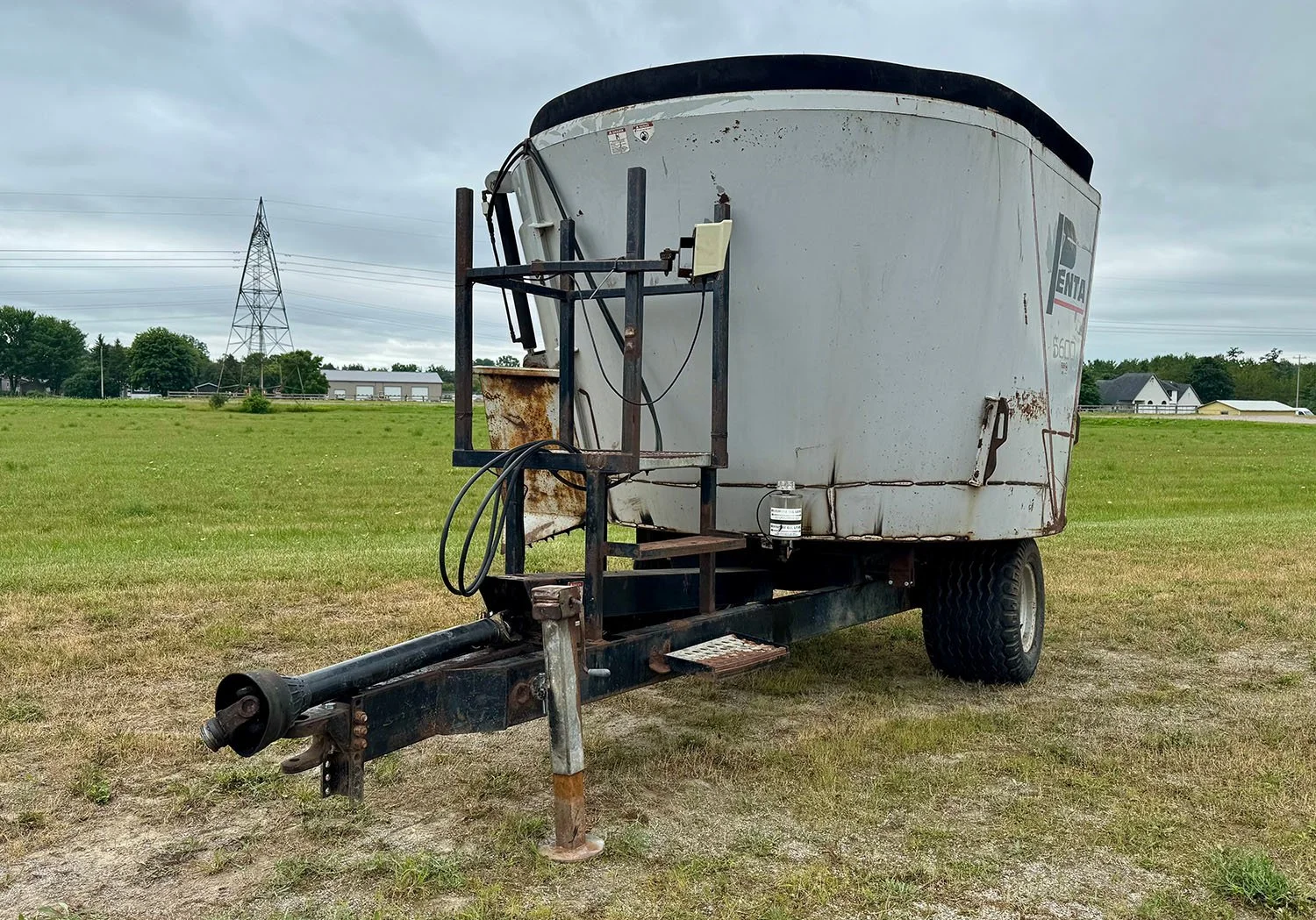 Front hitch view of a used Penta 5600 trailed vertical mixer showing PTO shaft and platform ladder.