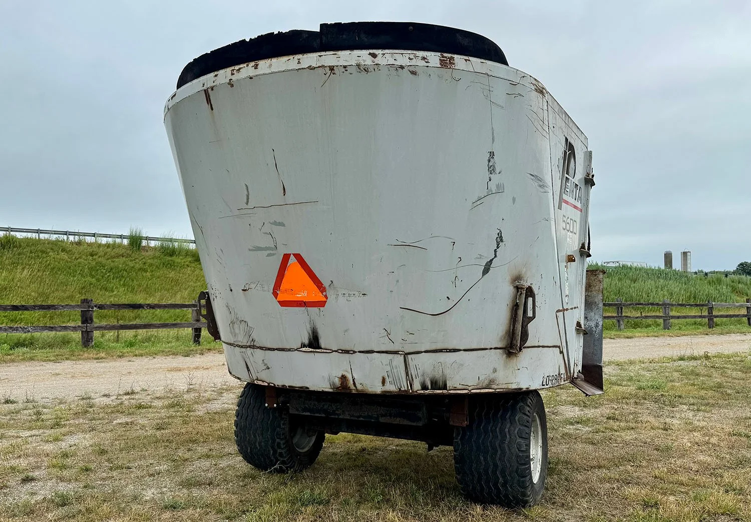 Rear view of a used Penta 5600 single axle vertical feed mixer with slow moving vehicle emblem.