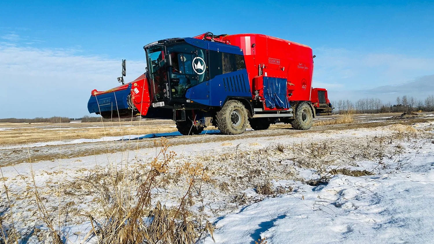 Low-angle view of a Siloking SelfLine System 500 plus 2519 maneuvering through a snow-covered field entry lane with its high-clearance ag tires.