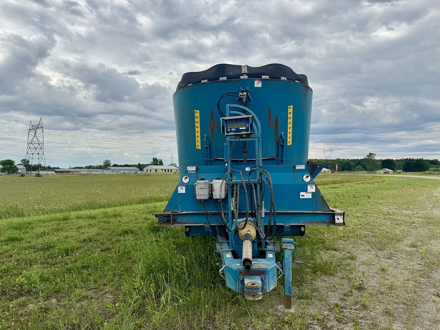 Straight front view of a blue Lucknow 2290 vertical TMR mixer wagon showing the hitch connection and mounted scale monitor.