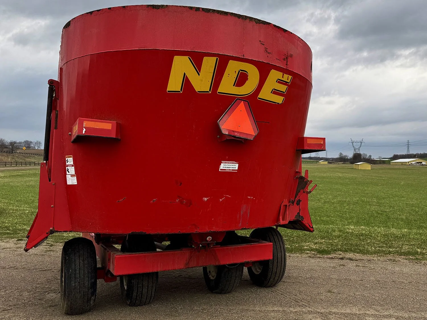 Rear view of a red used 2014 NDE 804 single auger vertical TMR mixer wagon showing the slow moving vehicle sign.