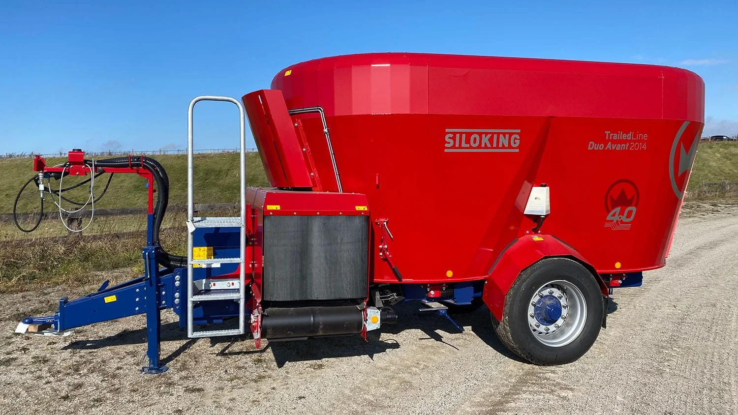 Side profile view of a red and blue Siloking TrailedLine Duo Avant 2014 twin-auger vertical mixer wagon highlighting the adjustable drawbar chassis.