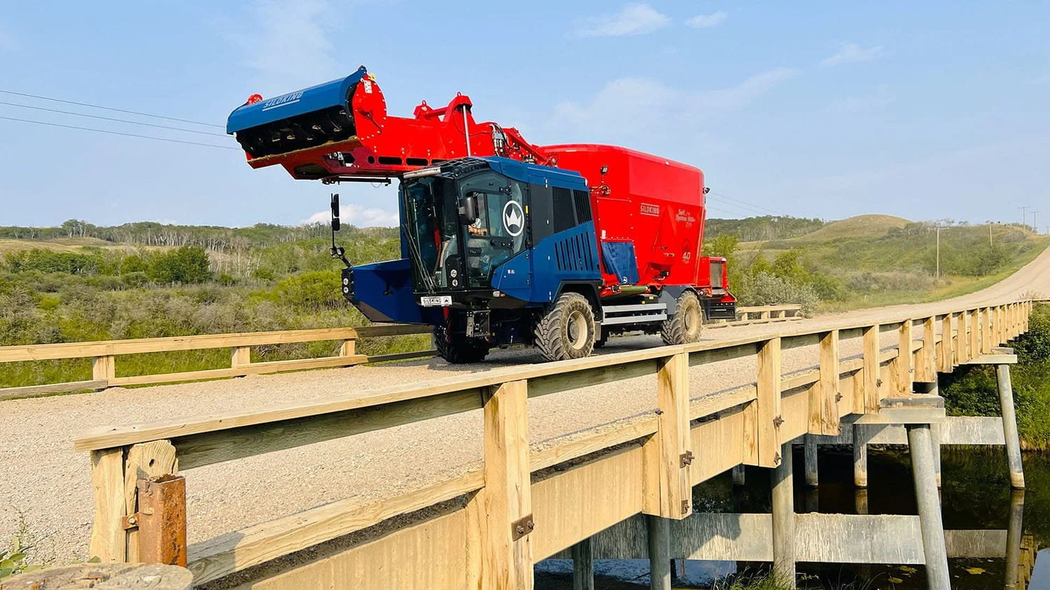 A Siloking SelfLine System 500 plus 2519 self-propelled TMR mixer crossing a bridge on a rural road during summer.