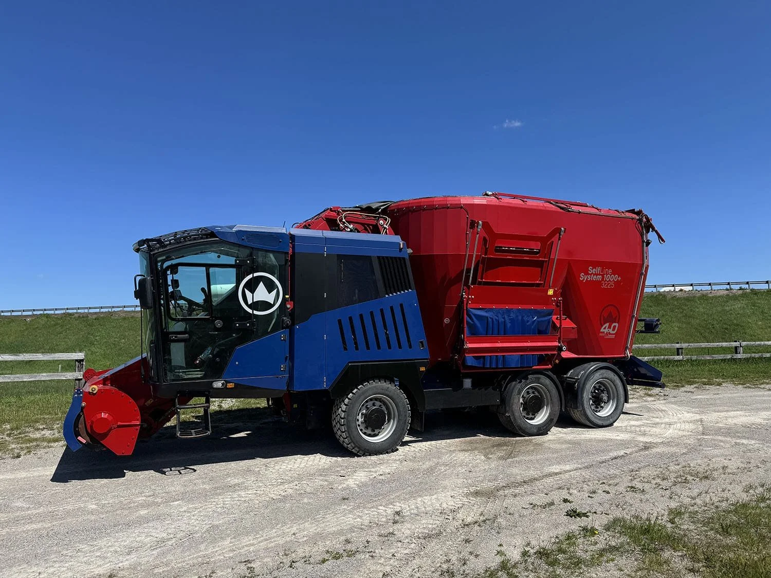 Left side profile view of a red and blue 2018 Siloking SelfLine 4.0 System 1000+ 3225 self-propelled vertical TMR mixer wagon on a three-axle chassis for sale at Siloking Canada.