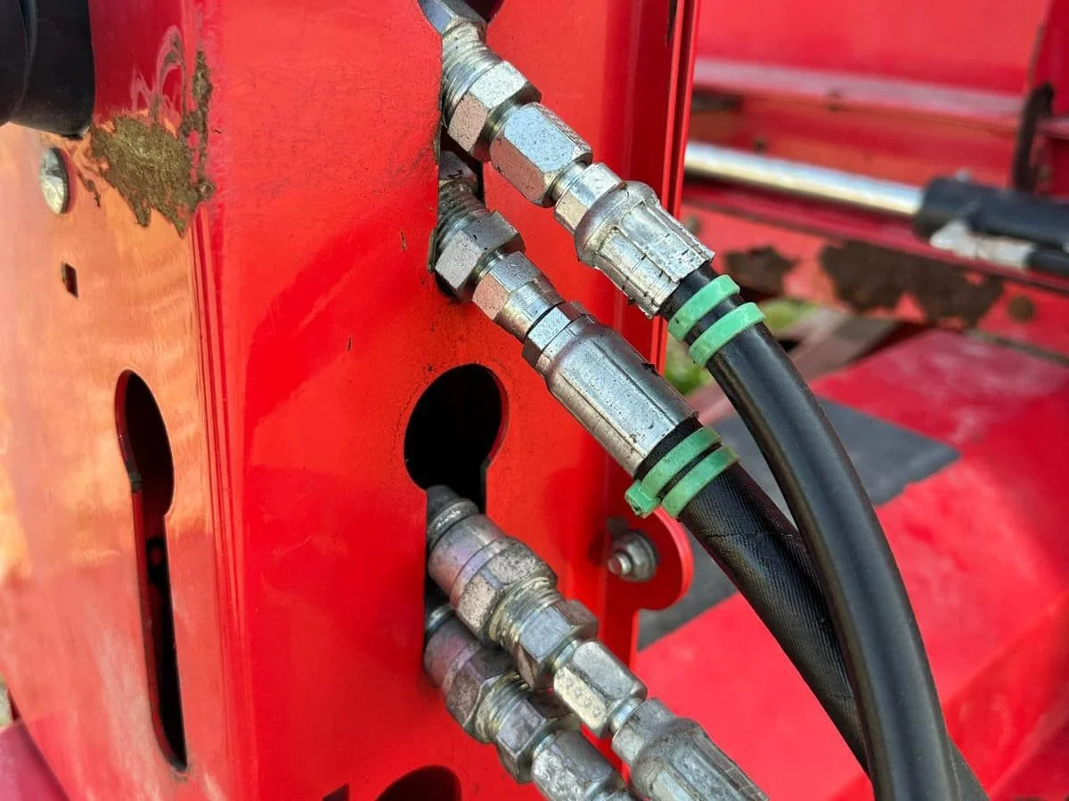 Close-up view of the color-coded hydraulic hose couplers and connections mounted on the front frame of a Rovibec trailed mixe