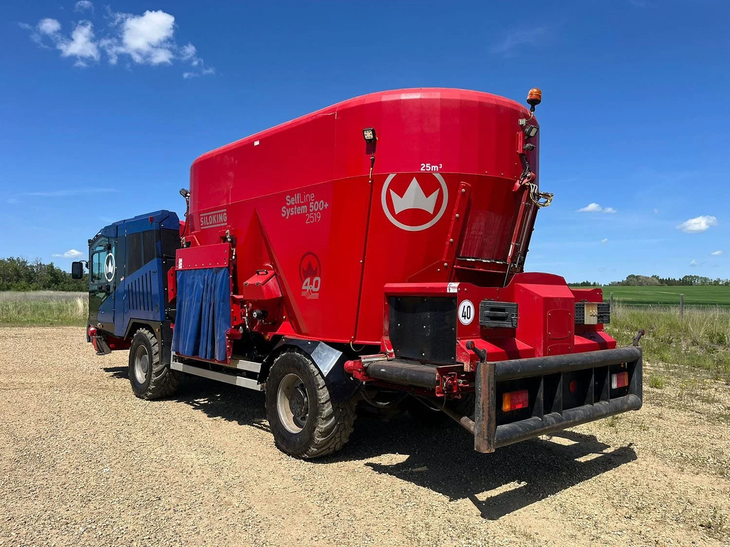 Rear three-quarter view of a red and blue 2020 Siloking SelfLine 4.0 System 500+ 2519-25 self-propelled TMR mixer displaying the rear cross conveyor.