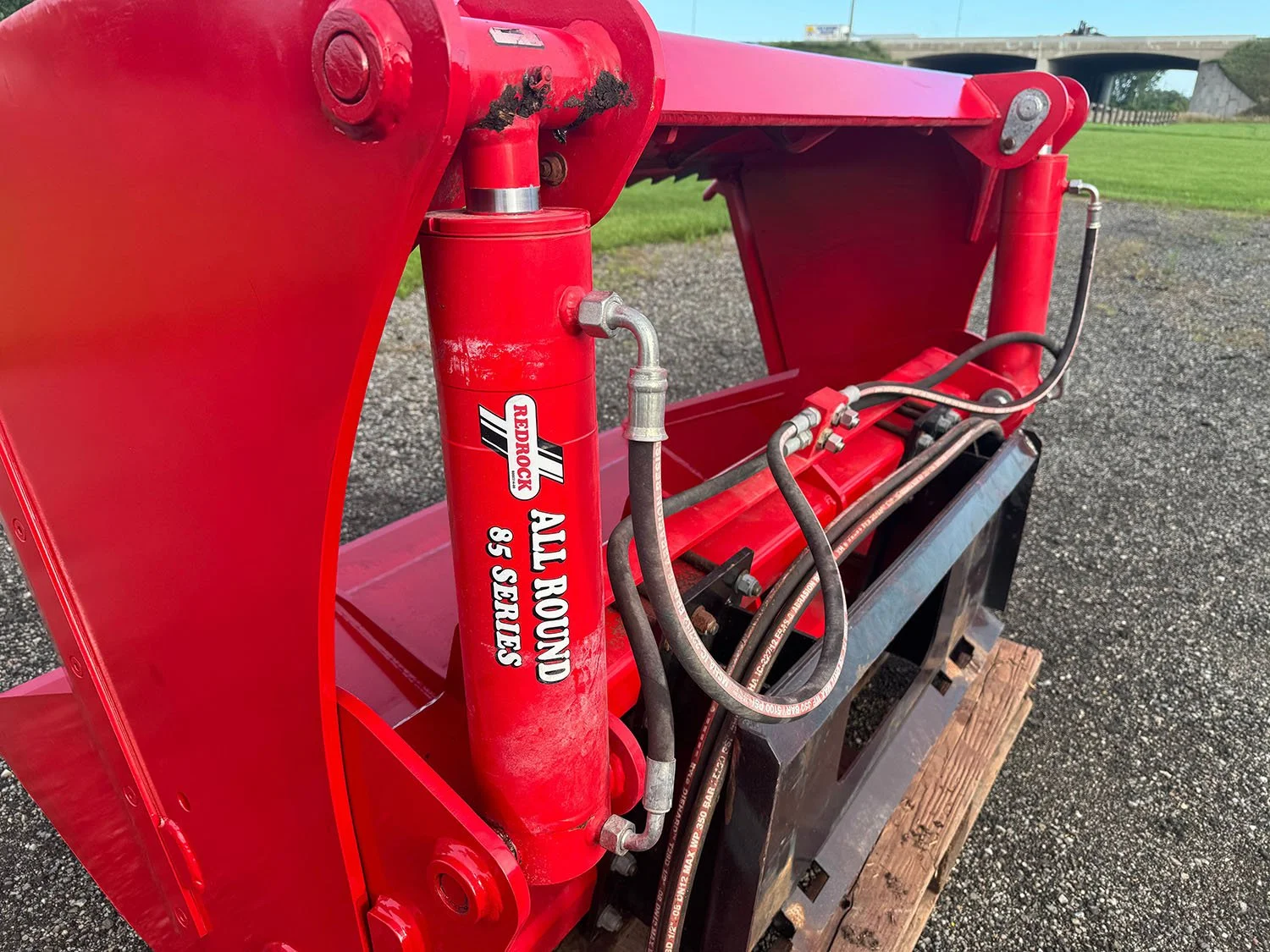 Close-up of the twin hydraulic cylinder setup and hose routing on a 2023 Redrock 180/85 shear bucket.