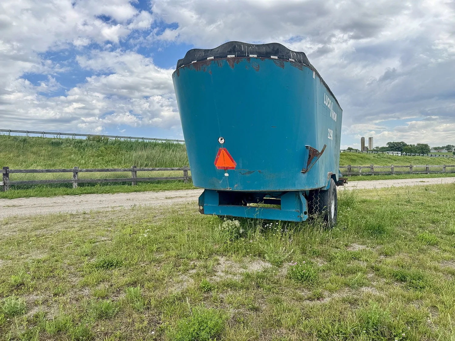 Straight rear view of a blue Lucknow 2290 vertical TMR mixer wagon showing the single axle tire configuration and safety reflector.