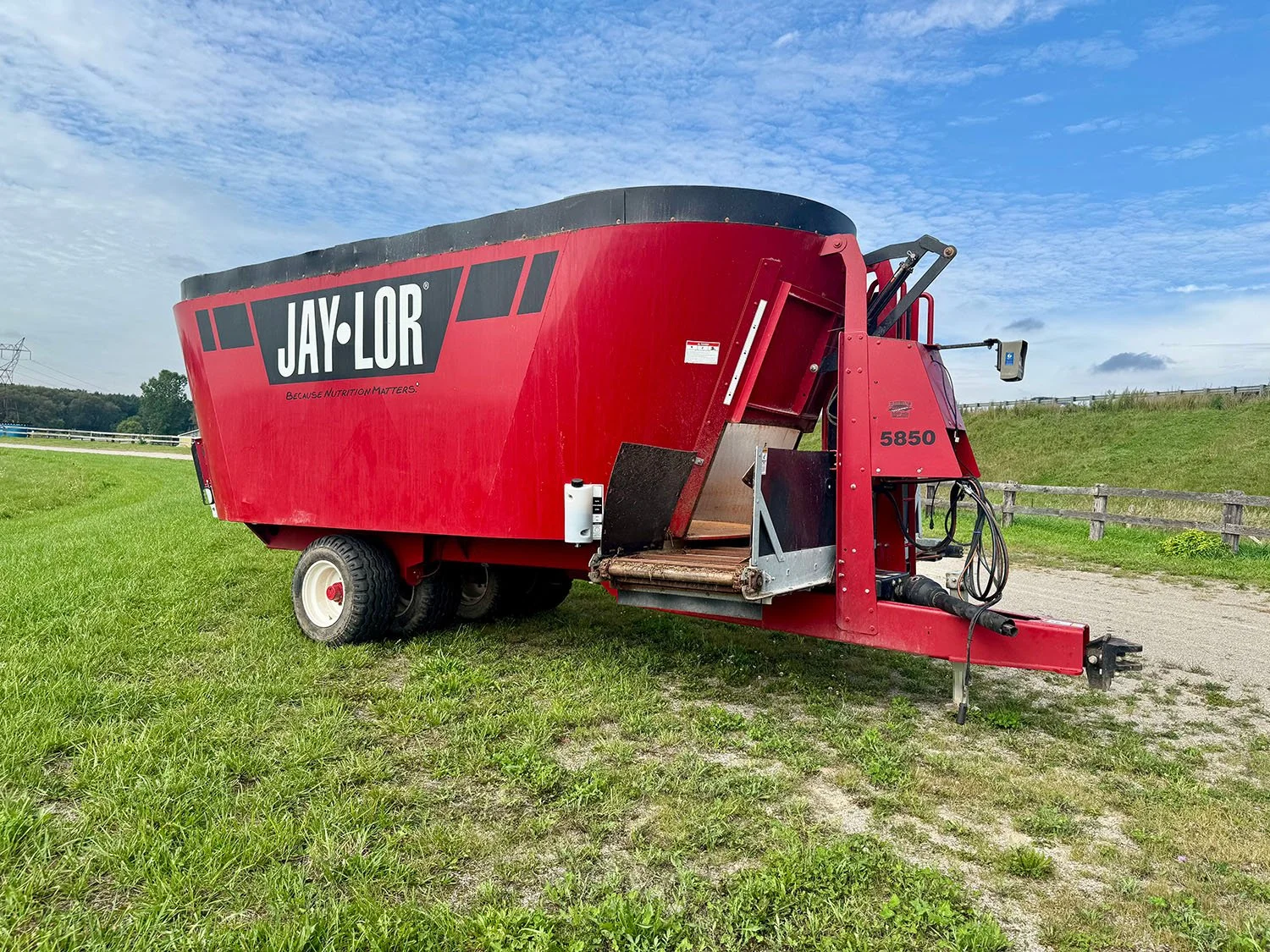 Full side view of a used 2021 Jaylor 5850 twin auger TMR mixer showing tandem axle assembly and front cross conveyor.