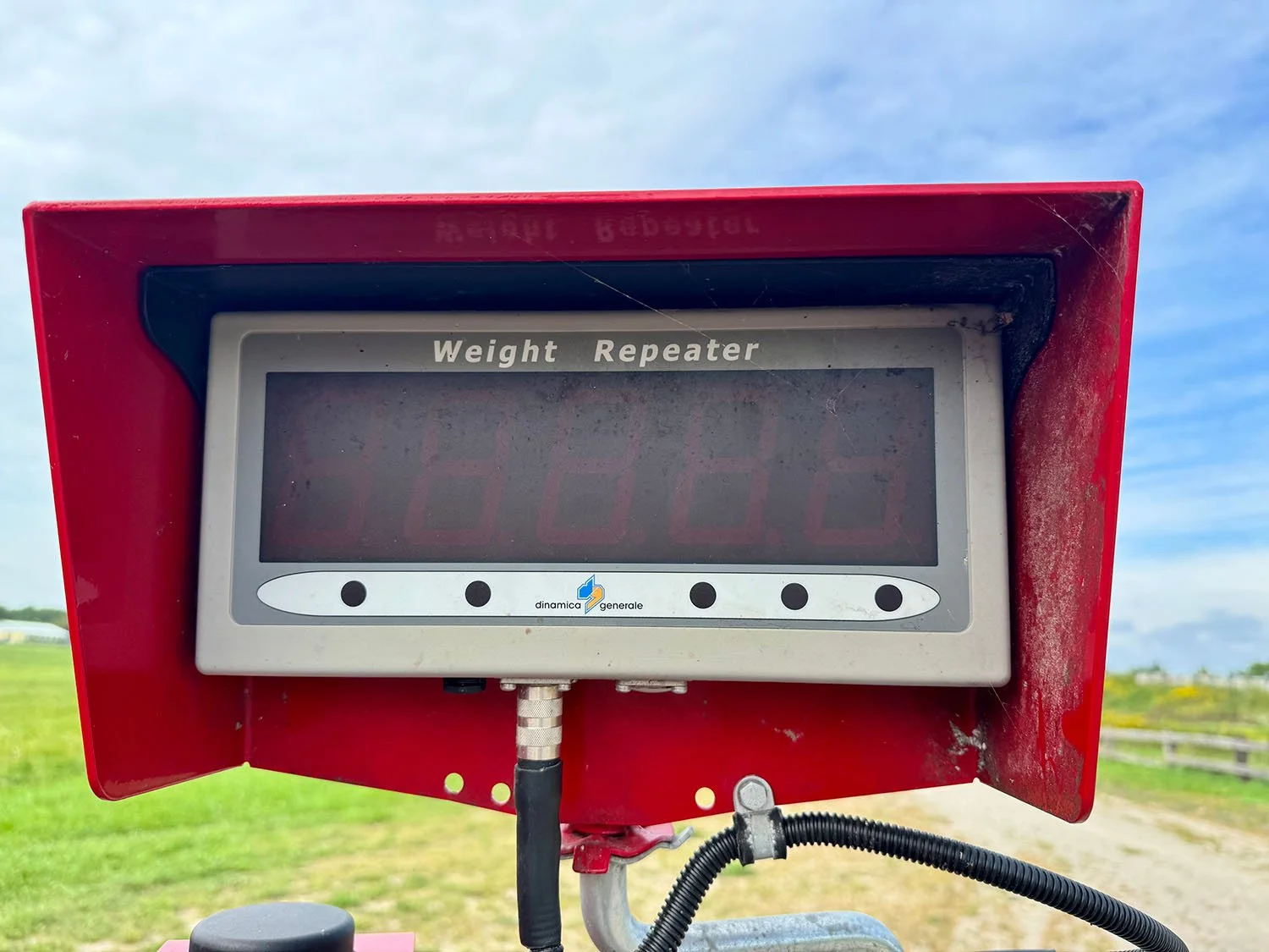 Close-up view of the Dinamica Generale electronic weight repeater scale indicator display head mounted under protective red sun visor.