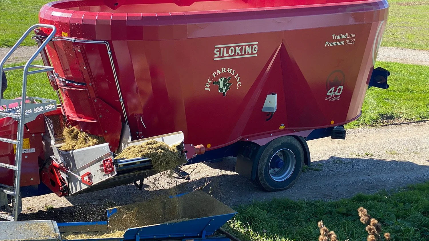 Close-up view of a Siloking TrailedLine Premium 3022 mixer wagon unloading fresh TMR ration via its hydraulic cross conveyor extension on a Canadian cattle farm.