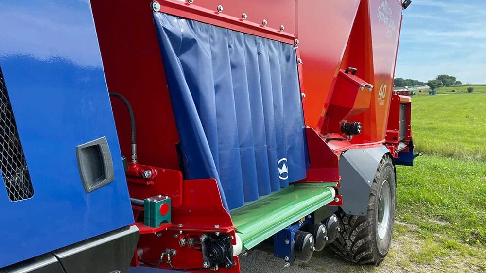 Close-up view of the heavy-duty hydraulic side discharge door and rubber protective curtain on a Siloking SelfLine self-propelled mixer wagon.
