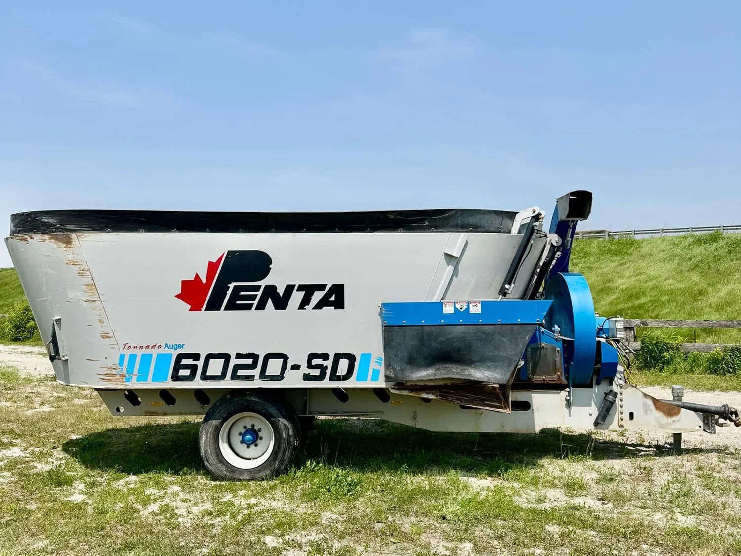 Left side profile view of a grey used Penta 6020-SD trailed twin auger vertical TMR feed mixer wagon featuring a front straw bedding blower assembly for sale at Siloking Canada.
