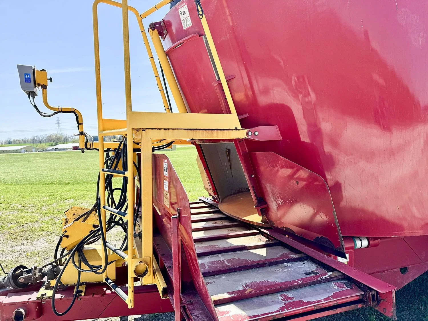 Detailed close-up view of the front cross conveyor discharge system with hydraulic sideshift functionality on a Supreme vertical mixer wagon.