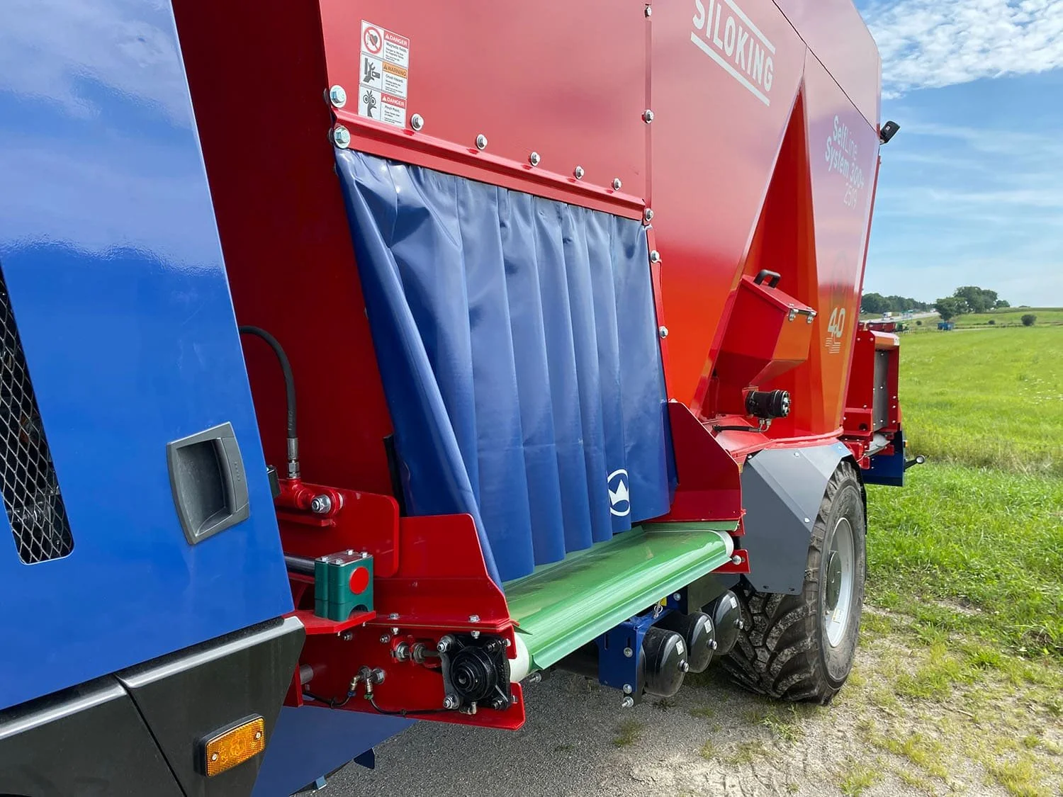 Close-up view of the left-hand discharge conveyor system on a new Siloking SelfLine 300+ 4x4 self-propelled feed mixer.