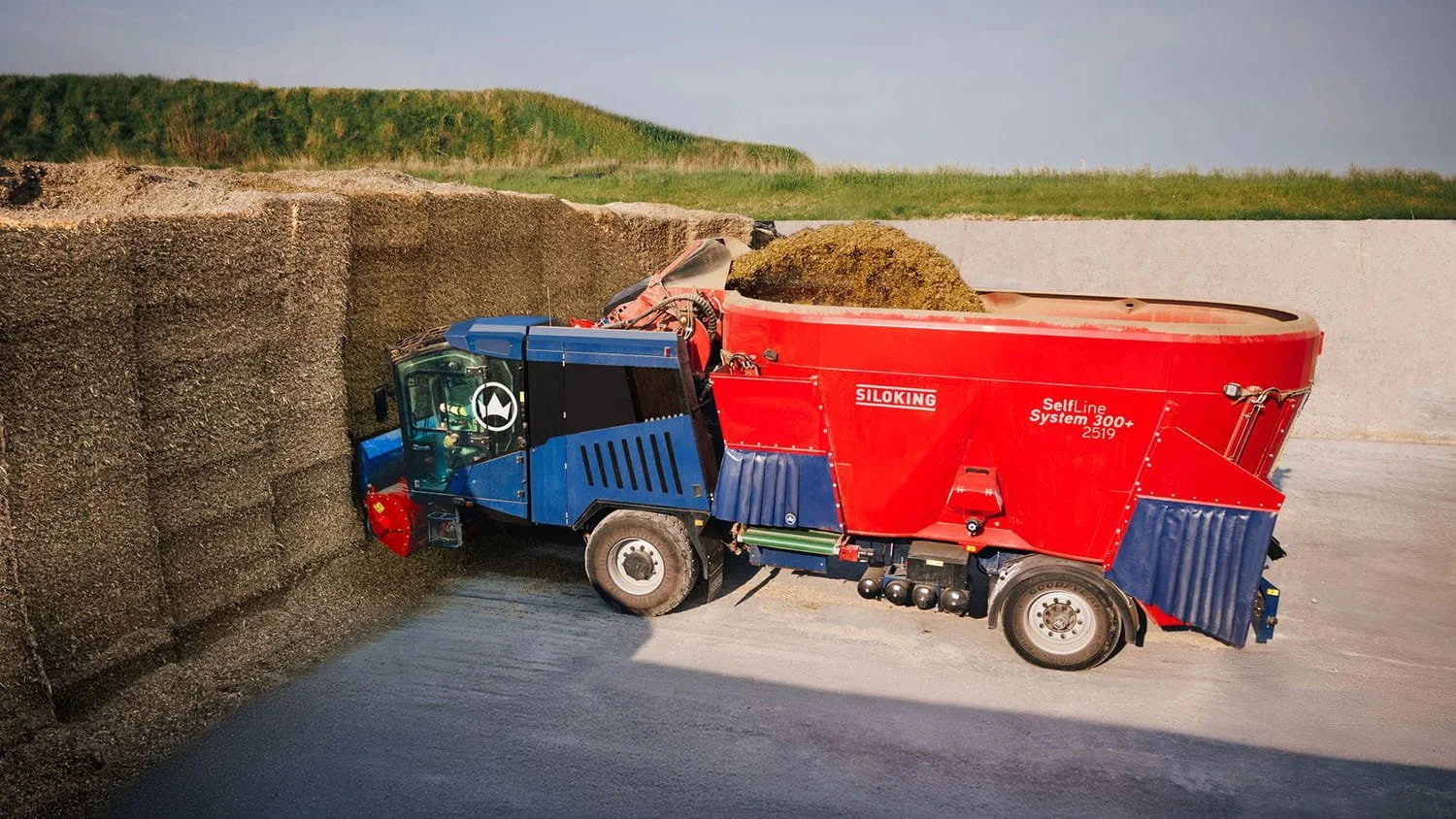 Side view of a Siloking SelfLine System 300 plus 2519 self-propelled mixer using its high-capacity milling arm to cleanly deface a silage bunk pit wall.